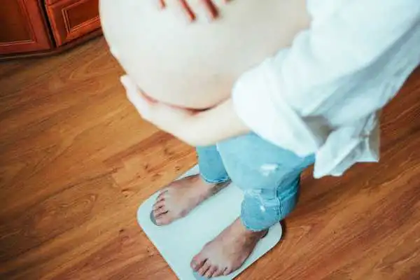 Image of woman weighing herself and experiencing weight gain through pregnancy Iver