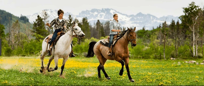 Confident plus-size woman riding Iver a horse through a field with a smile on her face.